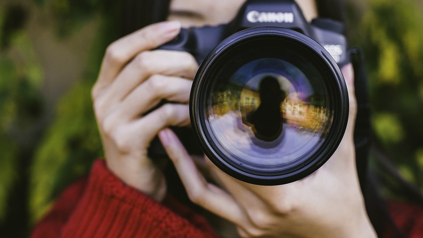 A photographer looking through a camera. Context for how visual representations are formed, not a model demonstration.